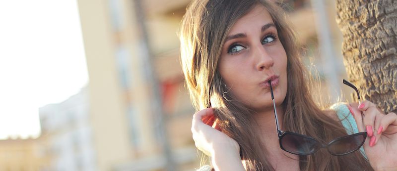 Woman looking sideways while holding pair of spectacles